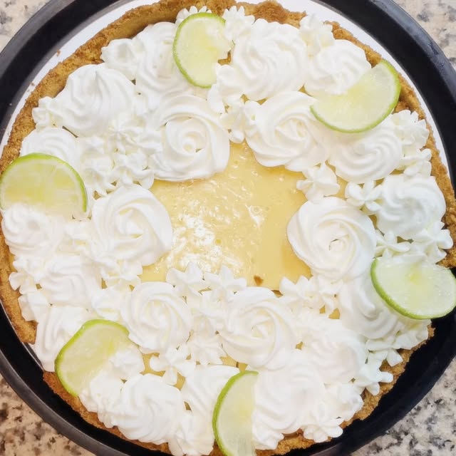 Key lime pie con copos de crema chantilly y rodajas de lima