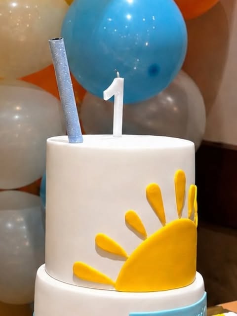 Torta de primer añito decorada con un sol amarillo, entre globos